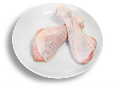 盘子家禽香菜白色板上的两条生鸡腿在白背景上被孤立图片