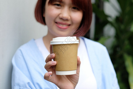 曼谷年轻的亚洲女人拿着咖啡杯长面容喝热饮女快乐的图片