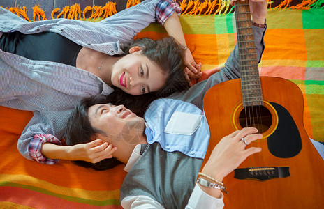以轻松和快乐的情感弹吉他来的年轻女和亚裔男女情侣人音乐家假期背景图片