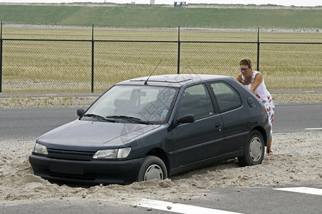 女人推着一辆汽车在沙滩上和小weels移动引擎服务图片