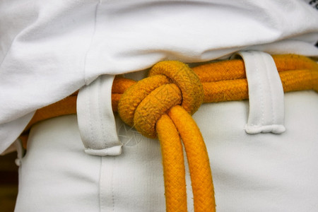 跆拳道腰带柔道穿着和服的男人身上黄色腰带很近结担背景