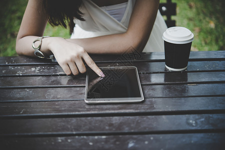 近身手握平板电脑在木制塔上桌子拿着平板电脑加一杯咖啡白色的指点女孩图片