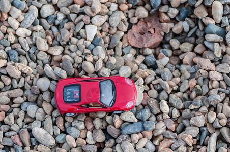 塑料结石红式现代玩具车在砂砾石上的浅地深处目图片