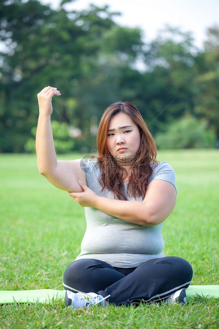 皮肤年轻的亚洲胖女人检查她的手臂脂肪不良图片