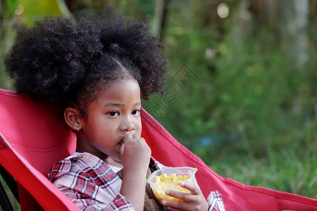 黑色的收成活力一个长着卷黑头发的年轻女孩饿了一碗玉米图片