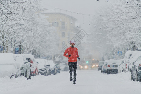 决心跑步年轻男子在城市的雪瀑下奔跑霜图片