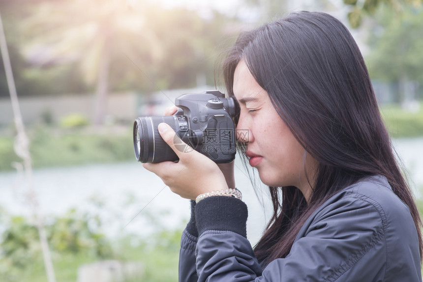 闲暇女孩服用在公园拍照的年轻亚洲女人图片