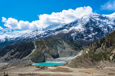 文布南村翠风景喜马拉雅山上美丽的雪峰和云彩在尼泊尔马南村附近的一个小绿化湖村庄背景