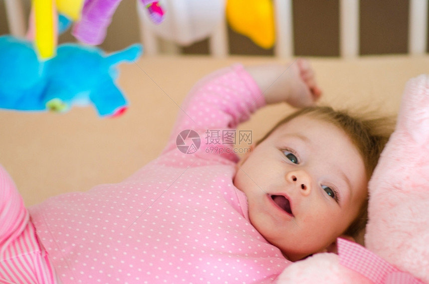 婴儿床微笑可爱的小女孩在床上玩一种图片