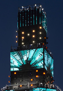 夜间活动的乐趣蓝色的人群多媒体塔夜间有许多发光的LED屏幕聚光灯和彩色霓虹效果具有音乐和灯光效果的娱乐活动背景