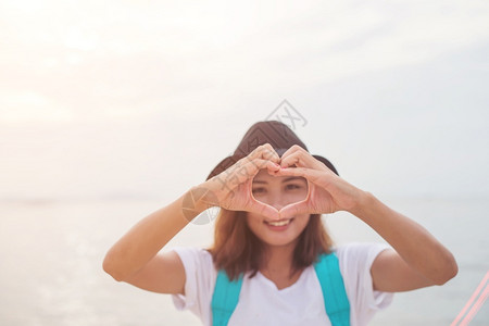 年轻女做心脏形状的女人夏日时光水平室外海边滩背景地平线洋黑色的图片
