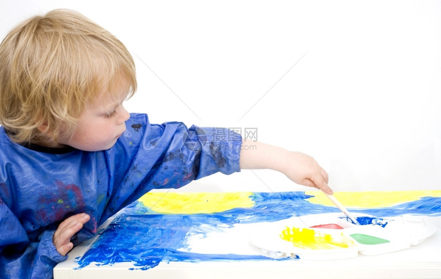 保持忙碌的画着蓝色海报的年轻男孩用刷子去寻找调色板手图片