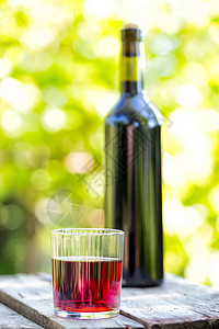 瓶装和面玻璃红酒在绿色叶子的模糊背景下喝瓶装和面玻璃红酒健康刻面葡萄图片