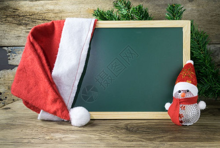 节日框架黑色板红圣诞礼帽和雪人玩具在老木头背景新的图片