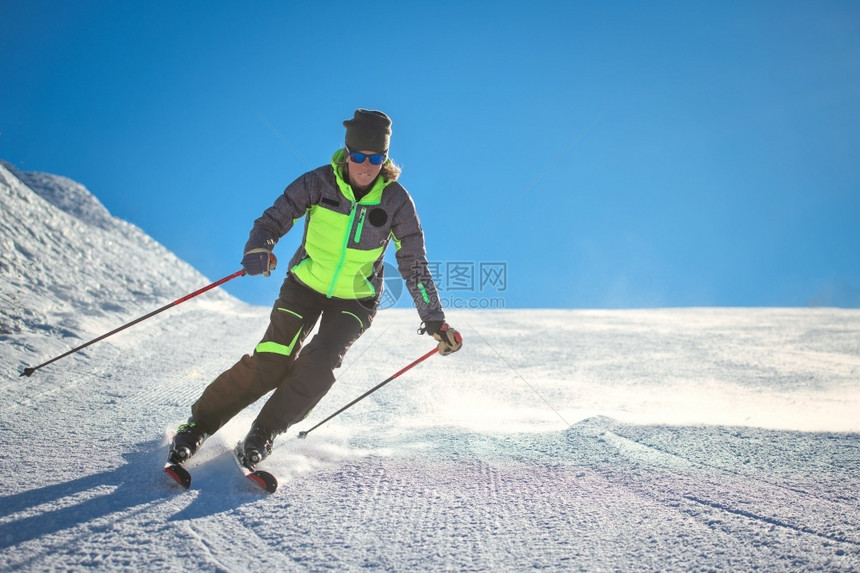 下坡在滑雪地区斜上的高山快乐者图片