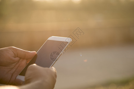 金融网络用智能手机亲近人与阳光一起在户外使用智能手机公司的图片