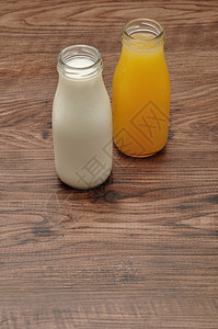 寒冷的饮料多汁瓶装牛奶和橙汁在木制背景下隔绝图片
