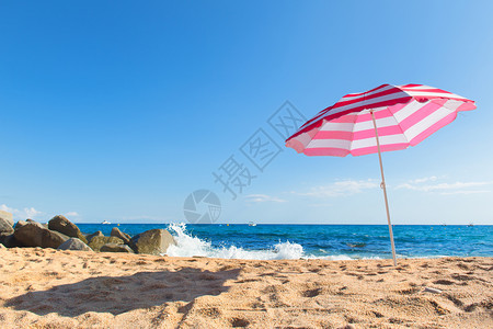 粗糙的空地平线清海滩有浪和条纹粉红色阳伞图片