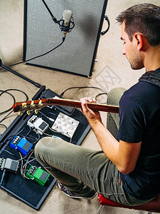 吉他踏板房间照片上一位男子在他的20岁晚期时在彩排演播室用他的电吉练习音乐手背景