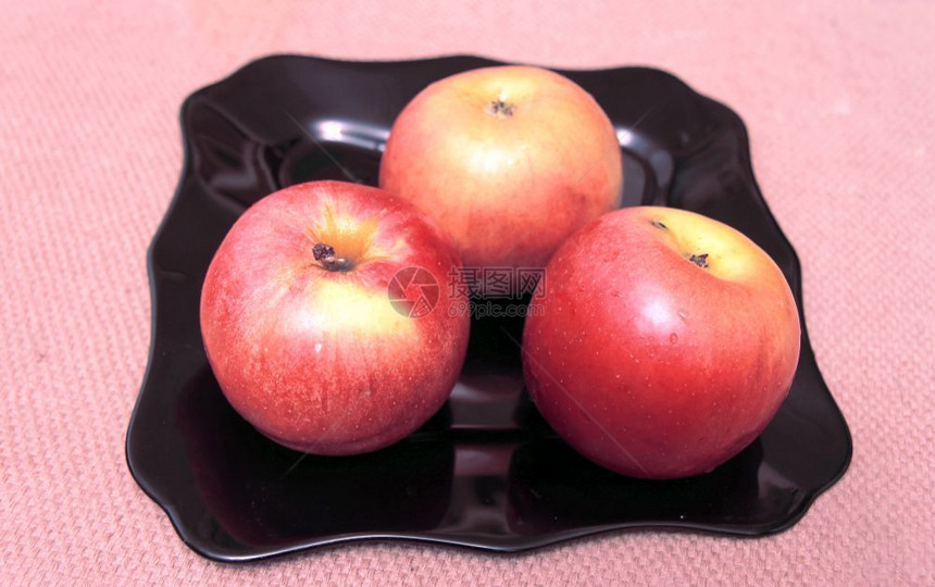 桌子上的黑盘有三个红苹果黑色的水团体图片