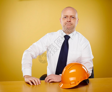 帽子一种男人办公室的工程师他穿着白衬衫和领带橙色硬帽在桌子上图片