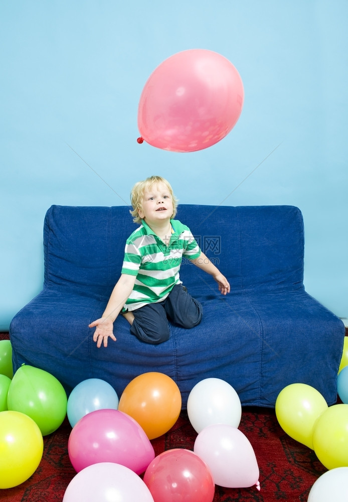 波斯语红色的微笑幼儿在沙发上玩气球图片