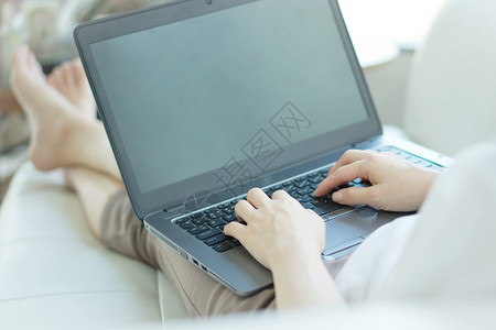 微笑成人生活在家沙发上使用笔记本电脑的临时年轻妇女侧边视图图片