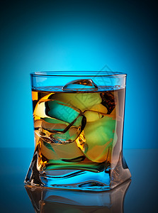 蓝色背景透明玻璃中加冰块的威士忌透明玻璃中加冰块的威士忌酒寒冷饮料图片