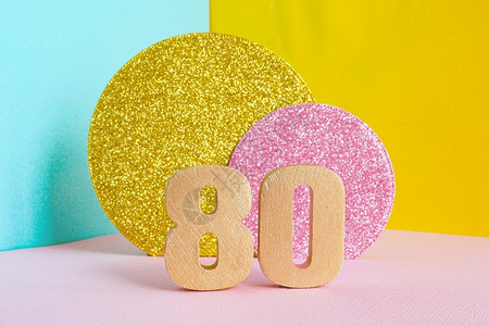 卡片等距金色80号子在多彩蓝黄色粉红背景上和两个闪亮的金子和粉红色圆圈生日快乐贺卡概念明亮的背景图片
