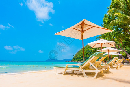 岛海岸拥有椰子棕榈树雨伞和椅子的美丽热带海滩和滨景观促进彩色加工白的图片