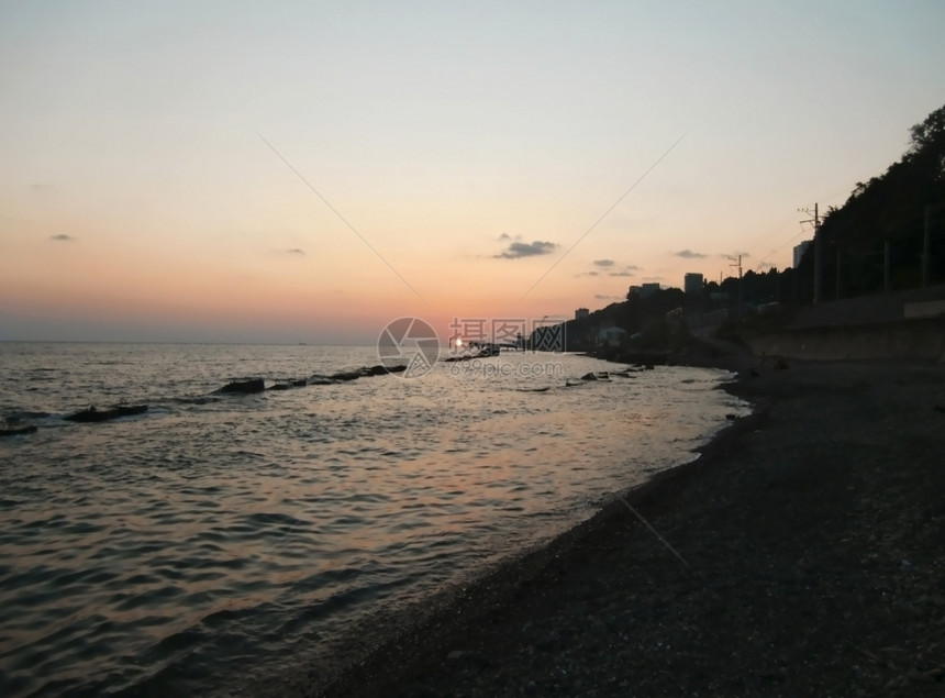 环太阳在黑海上坠落超过热的海滩图片
