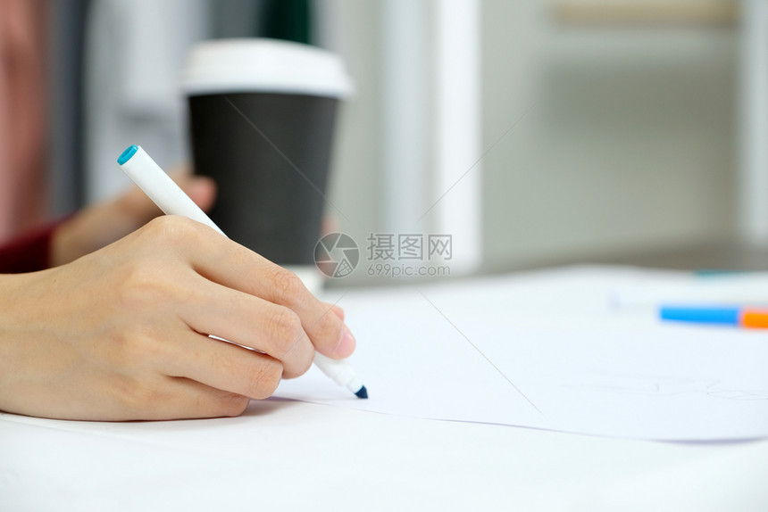 蓝色的标记写近身手握着蓝笔的女子在桌背景的白纸上图片