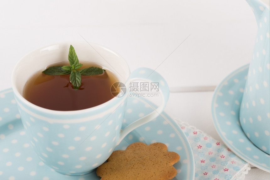 满的蒸汽有薄荷饼干的茶放在瓷杯和碟子里温暖的图片
