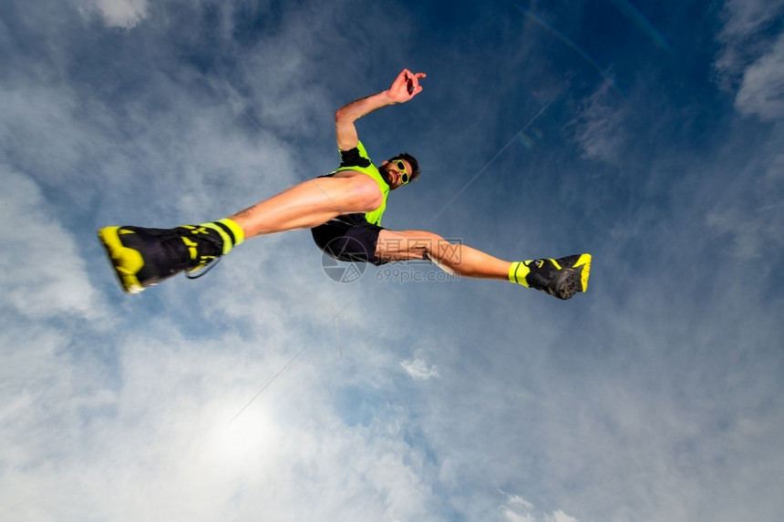 岩石男子运动员在山上奔跑的足迹中跳跃时积极的竞技图片
