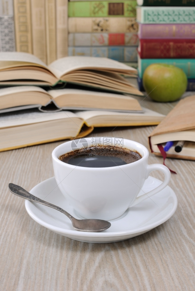 锻炼咖啡因桌子上一杯咖啡背景是一本开着的书上面有一本笔记和堆书鲜酿图片