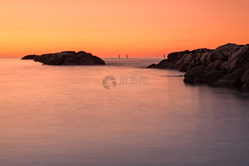 黎明海面前的橙色日落海水前的橙色日落和海面的石头自然平静图片