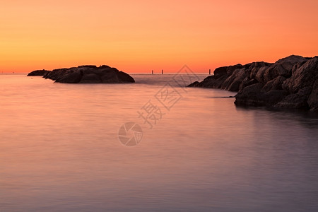 黎明海面前的橙色日落海水前的橙色日落和海面的石头自然平静图片