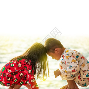 在海边坐着玩耍的两个孩子图片