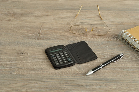 会计工作木制背景显示的计算器笔阅读眼镜和记本纸图片