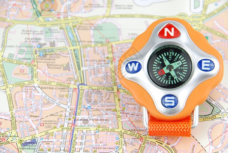 城市旅行概念上的橙色罗盘磁铁目的地形背景图片