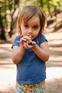 远足小路金发女孩手上拿着橡子的小桃用背包在森林的路上种子图片
