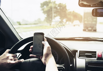 近距离接一个男子使用移动电话危险驾驶汽车的人和尽管窗户门图片