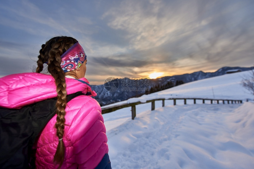 雪鞋行走活动女孩在山上漫步时看着日落图片