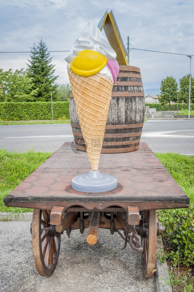 吃乳制品巨大的配有塑料冰淇淋和红酒桶的农车图片