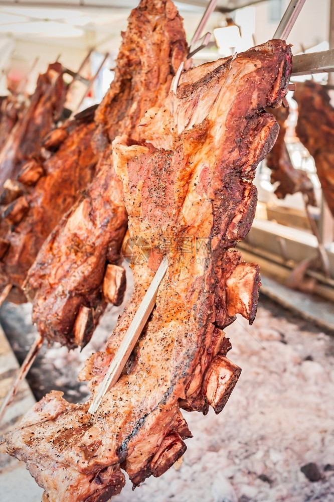 大约在阿根廷传统烧烤餐盘Asado附近放置的垂直烤炉上煮熟的牛肉纳达林炙图片
