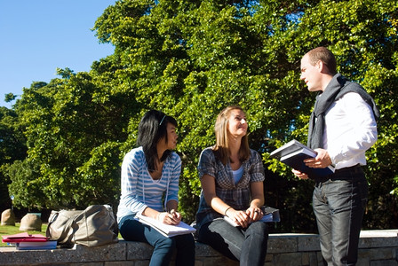 三个学生在一美丽的阳光明媚日子在一所大学公园的面小墙上说话理由人们亚洲背景图片