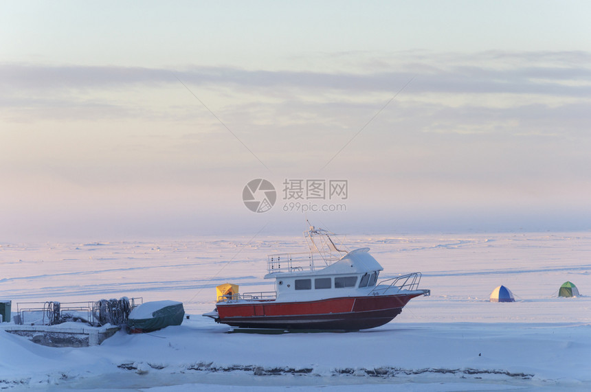 在俄罗斯阿尔汉盖克的北德维纳河岸上一艘冷冻的摩托艇停靠在苍白站立冰图片