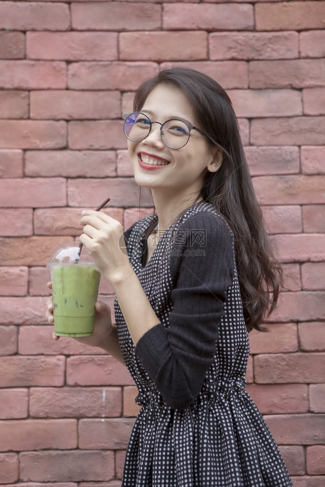 年轻的青女和手握的冰杯绿茶饮料快乐的漂亮幸福图片