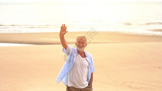 快乐老人手在沙滩上图片