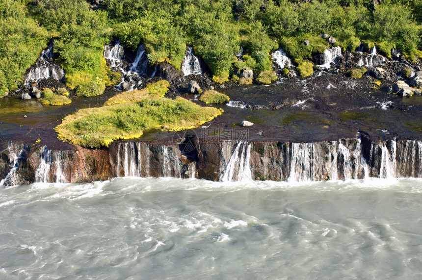 壮观的Hraunfossar级联冰岛的一个瀑布在那里自然泉源供应来兰花山脉的水覆盖着灌木草丛和苔一种河阳光照射图片